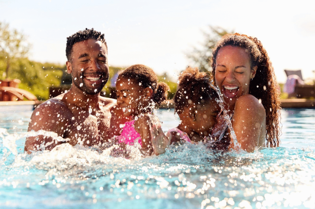 A family of four has fun in a bright blue pool laughing and playing together under the warm sun
