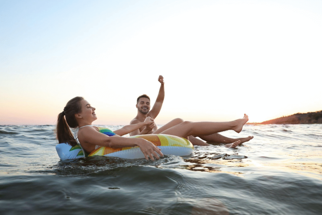 A man and woman relax on an inflatable raft floating in the ocean under a clear blue sky