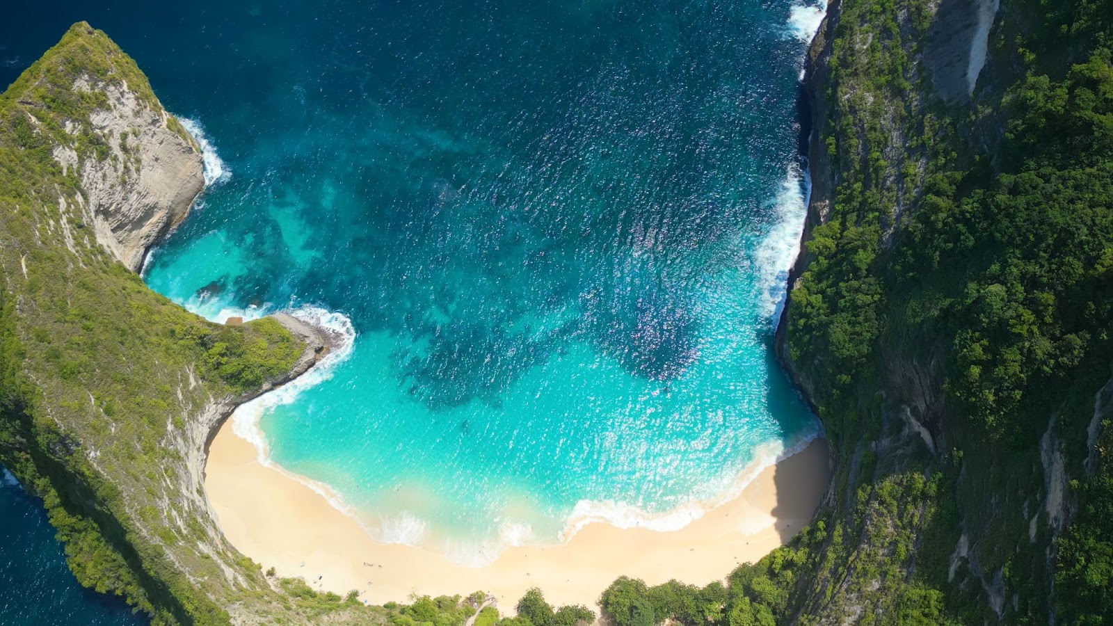 Aerial view of Kelingking Beach's T-Rex-shaped cliff and turquoise cove in Nusa Penida, Bali.