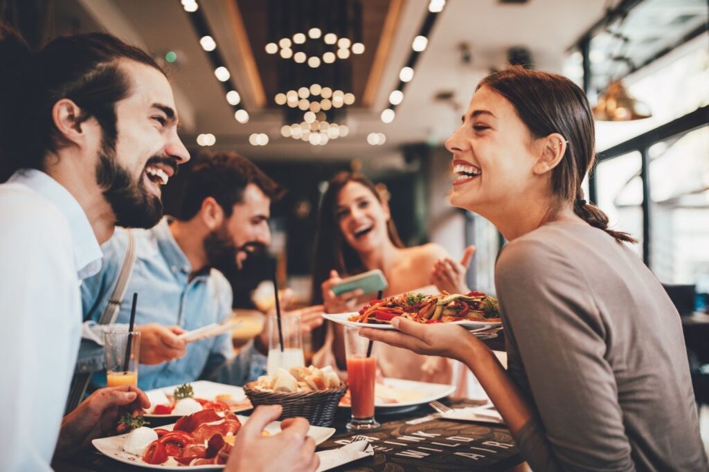 A group of friends laughing and sharing a meal together at a restaurant.