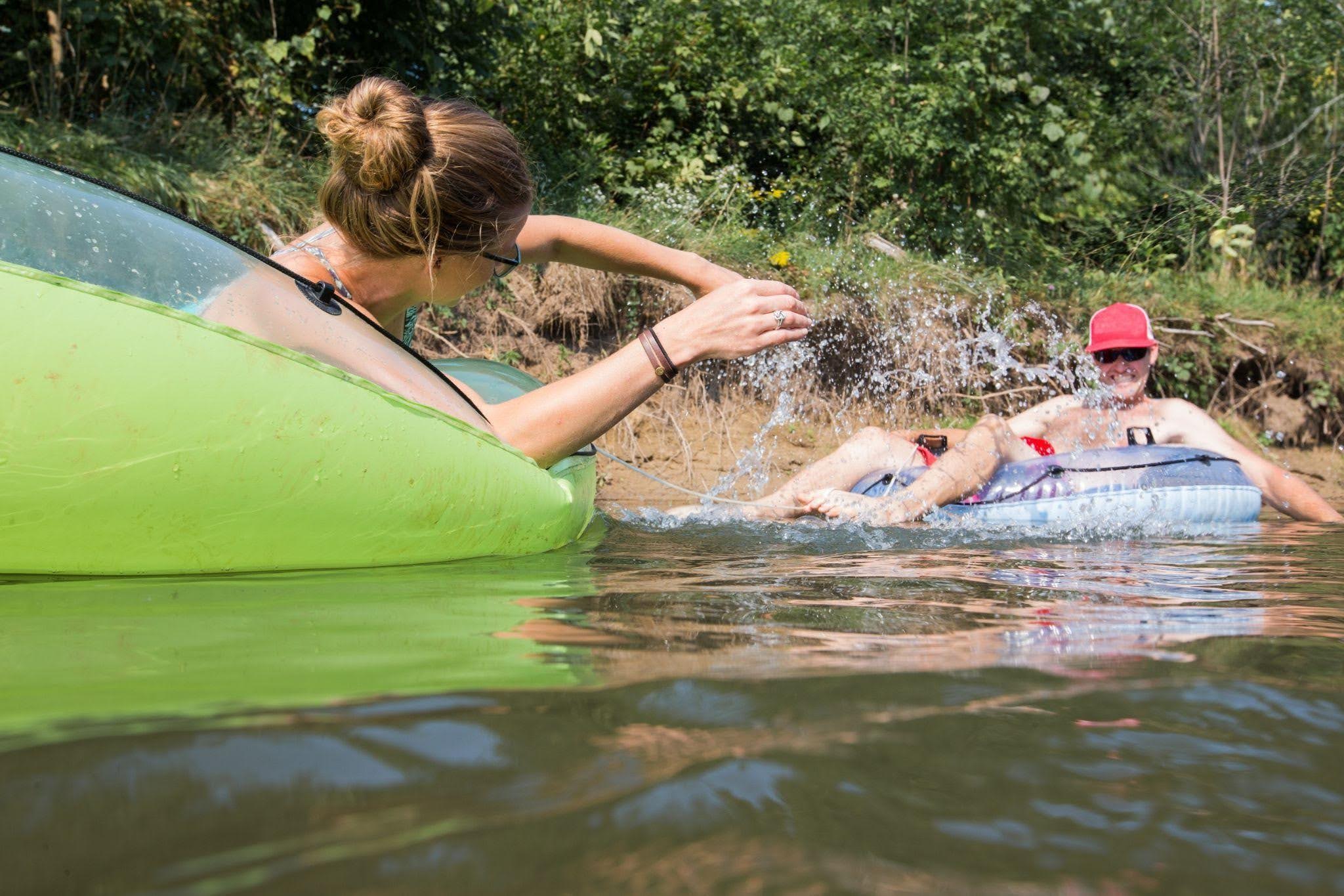 A man and woman are leisurely floating in tranquil water enjoying a sunny day