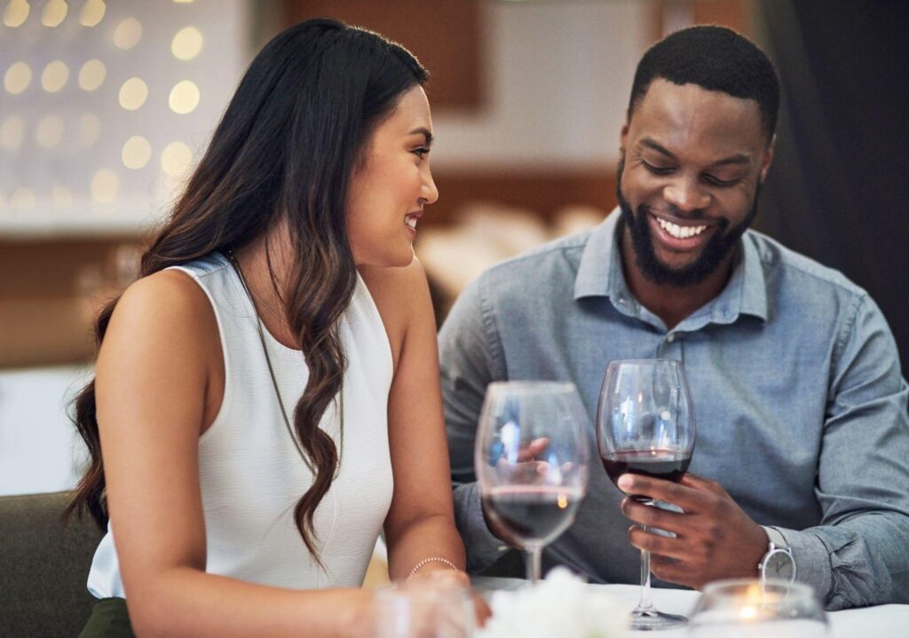 A smiling couple holds wine glasses enjoying a joyful moment together
