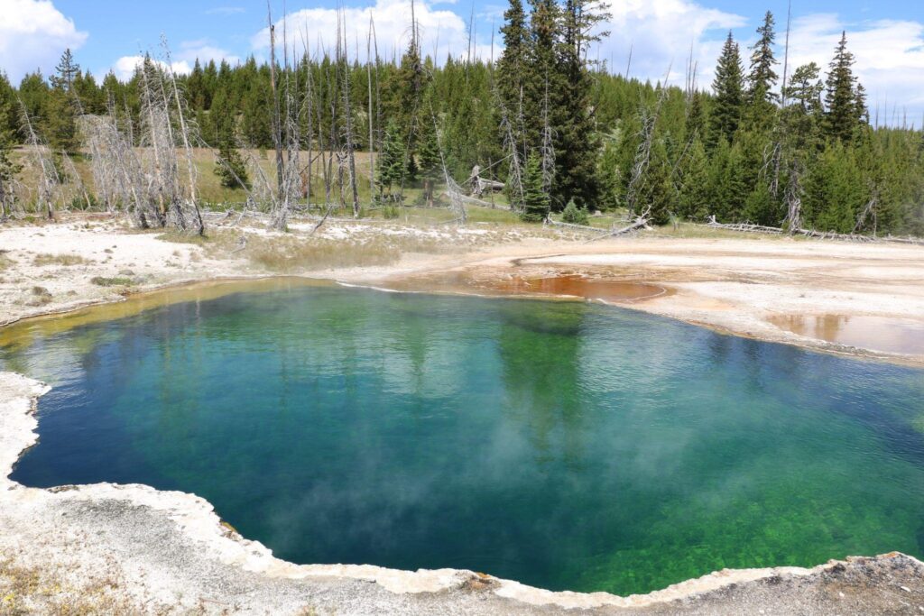 A large tranquil pool of water reflecting the surrounding landscape under a clear blue sky