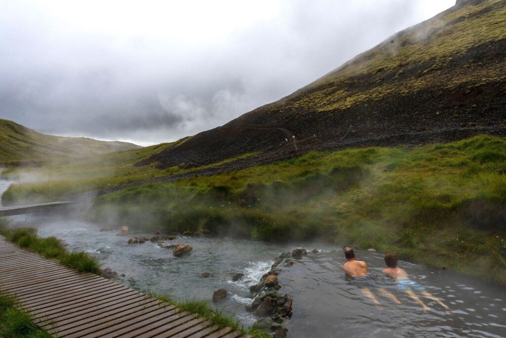 People swimming in a natural hot spring amid majestic mountains