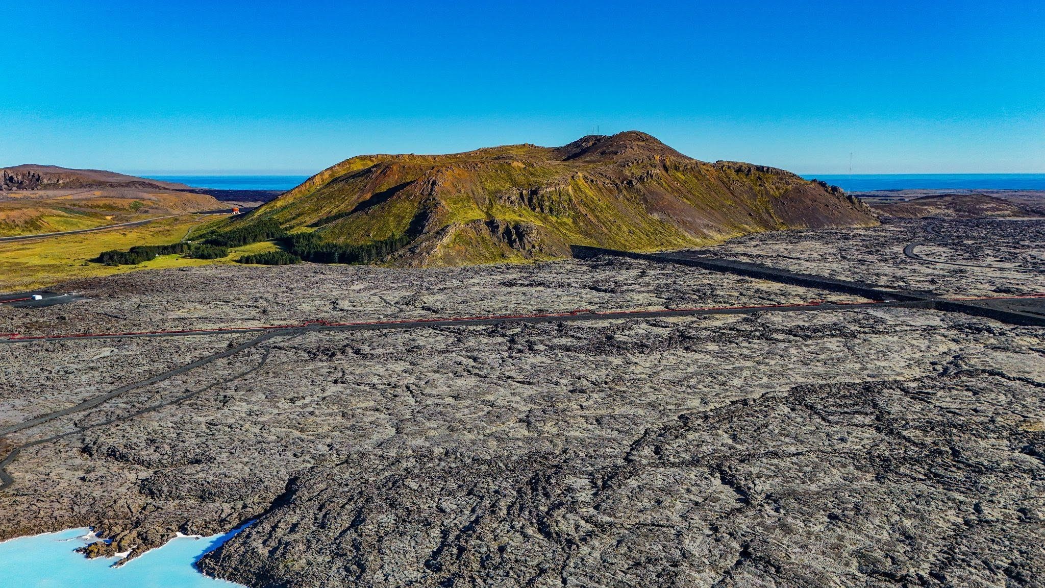 Aerial perspective of a lava field surrounded by mountains illustrating the stark contrast between the landforms